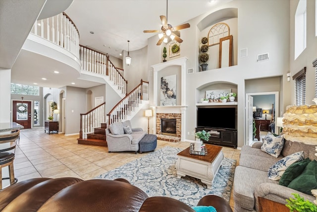 living room featuring light tile patterned flooring, a high ceiling, ceiling fan, a brick fireplace, and built in shelves