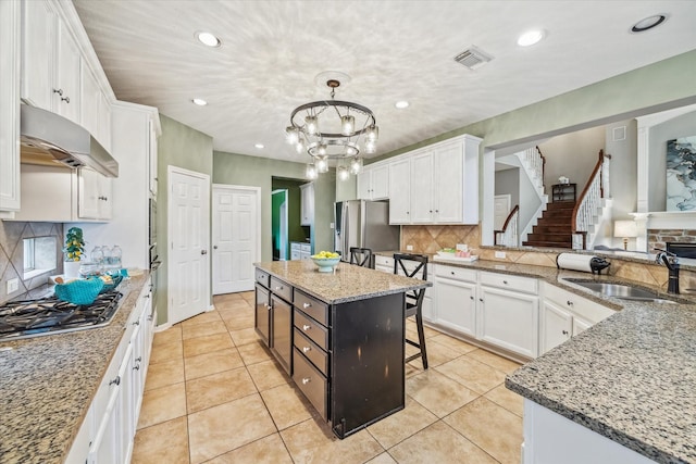 kitchen with stainless steel appliances, sink, a kitchen island, and white cabinets