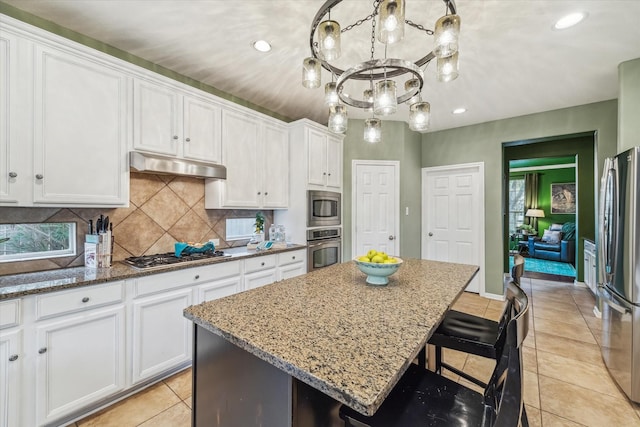 kitchen featuring white cabinetry, a kitchen island, light stone countertops, and appliances with stainless steel finishes