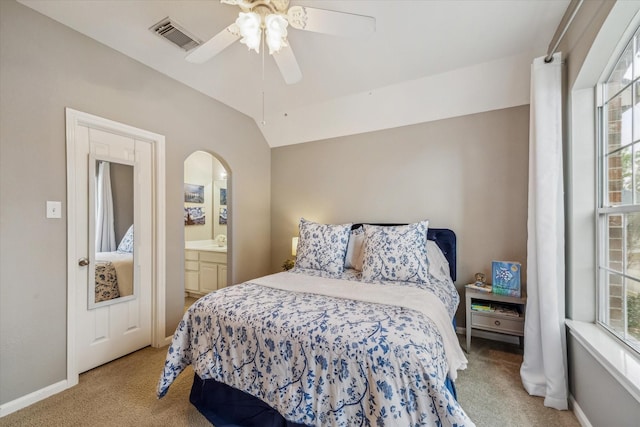 bedroom featuring ceiling fan, lofted ceiling, ensuite bath, and light carpet