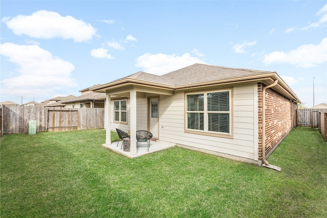 rear view of house featuring a patio, a fenced backyard, brick siding, a shingled roof, and a yard