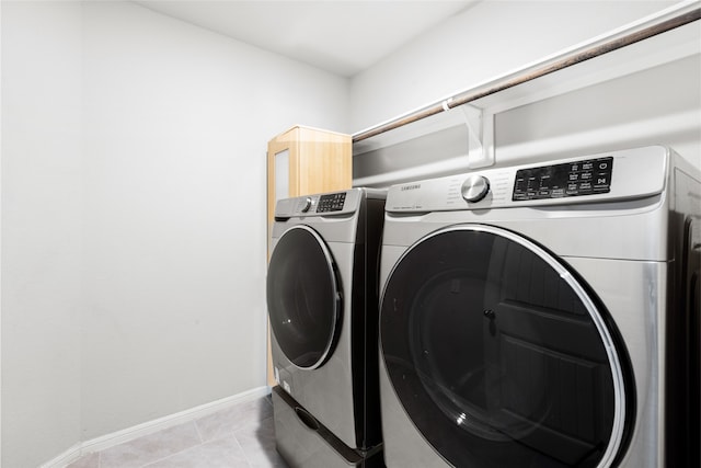 clothes washing area featuring laundry area, independent washer and dryer, baseboards, and light tile patterned floors