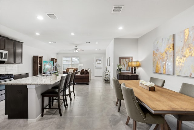 kitchen with visible vents, an island with sink, open floor plan, stainless steel appliances, and a sink