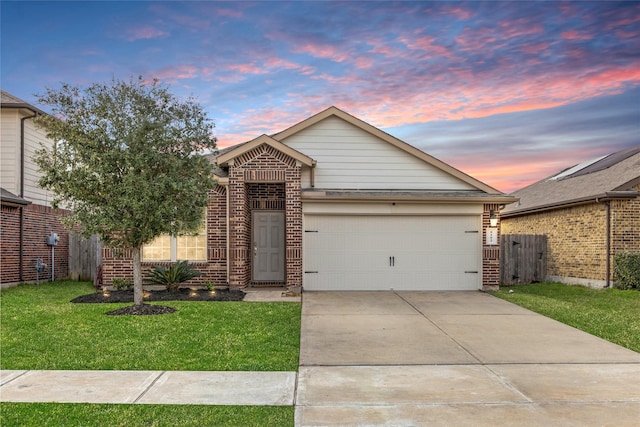 view of front of house featuring an attached garage, a lawn, concrete driveway, and brick siding