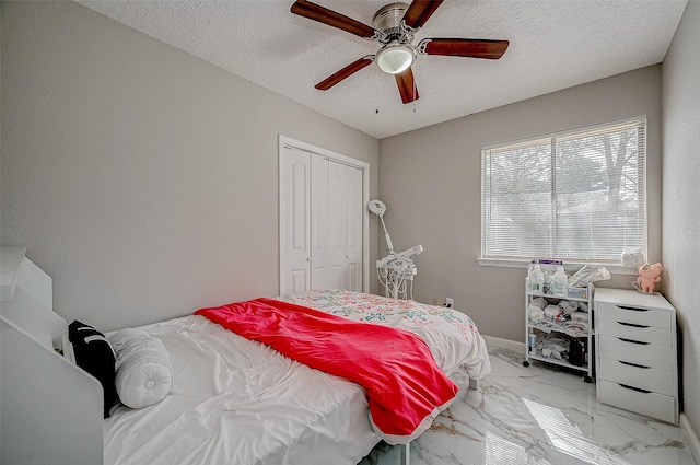 bedroom with marble finish floor, a textured ceiling, a ceiling fan, and a closet