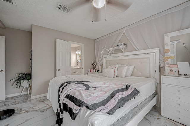 bedroom featuring marble finish floor, visible vents, a textured ceiling, ensuite bath, and baseboards