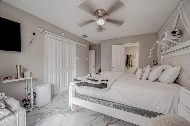 bedroom featuring marble finish floor, a closet, visible vents, ceiling fan, and a textured ceiling