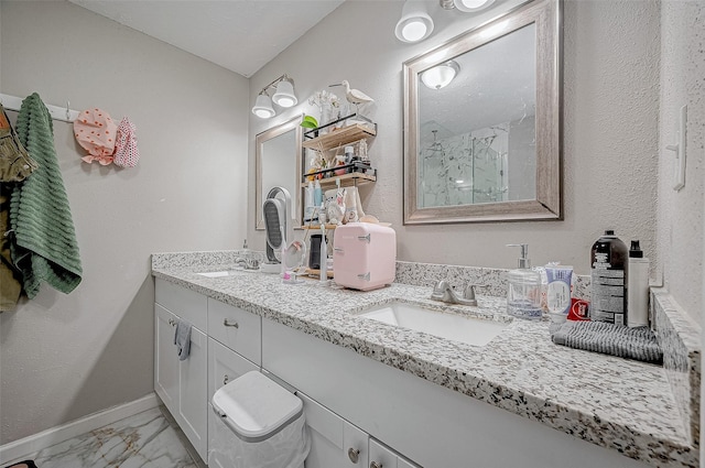 bathroom featuring marble finish floor, a marble finish shower, baseboards, and a sink