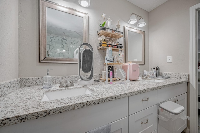 bathroom featuring double vanity, walk in shower, a sink, and a textured wall