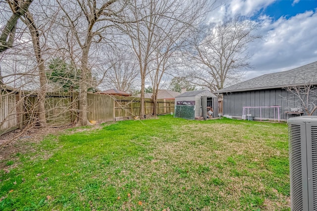 view of yard featuring a fenced backyard, a shed, cooling unit, and an outbuilding