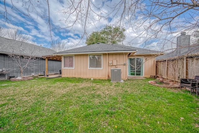 back of house with central AC, a lawn, fence, and board and batten siding