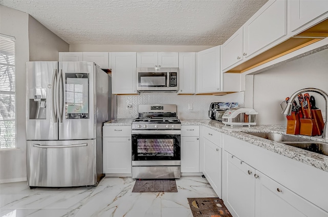 kitchen with marble finish floor, stainless steel appliances, tasteful backsplash, white cabinetry, and a sink