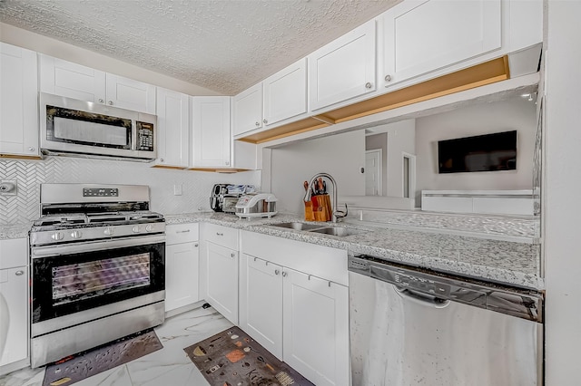 kitchen with marble finish floor, white cabinetry, appliances with stainless steel finishes, and a sink