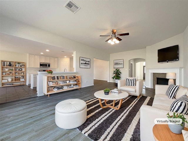 living room with ceiling fan and dark hardwood / wood-style flooring