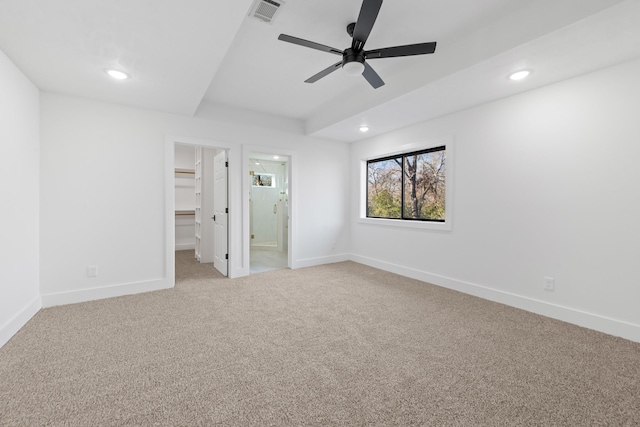 unfurnished bedroom with a spacious closet, light colored carpet, ceiling fan, ensuite bath, and a closet