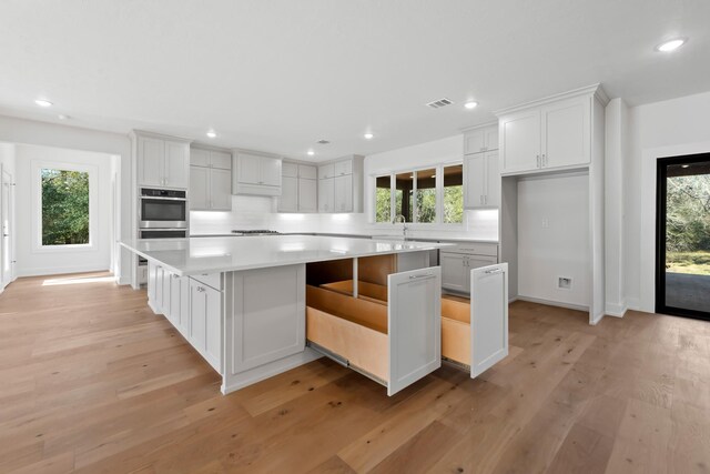 kitchen with a large island, a kitchen breakfast bar, light wood-type flooring, and white cabinets