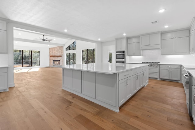 kitchen featuring a fireplace, light hardwood / wood-style floors, a kitchen island, and backsplash