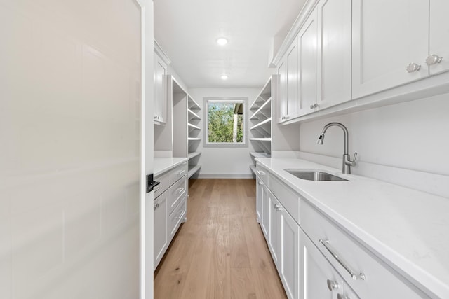 kitchen with white cabinetry, sink, and light hardwood / wood-style floors