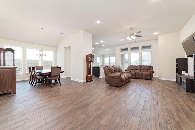 living room featuring lofted ceiling, ceiling fan with notable chandelier, light hardwood / wood-style flooring, and a wealth of natural light