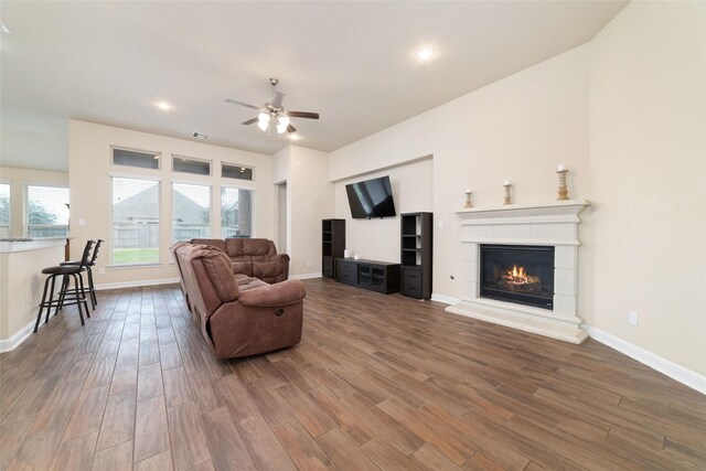 living area featuring a glass covered fireplace, wood finished floors, and baseboards