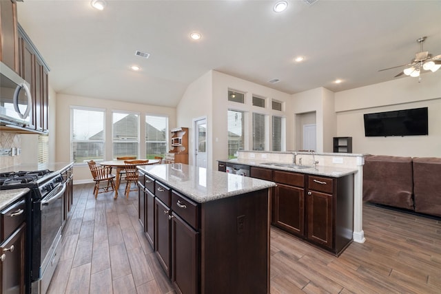 kitchen featuring sink, dark brown cabinets, a kitchen island, hardwood / wood-style flooring, and stainless steel appliances