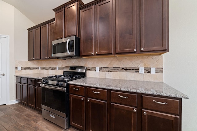 kitchen featuring light stone counters, decorative backsplash, stainless steel appliances, and dark brown cabinetry