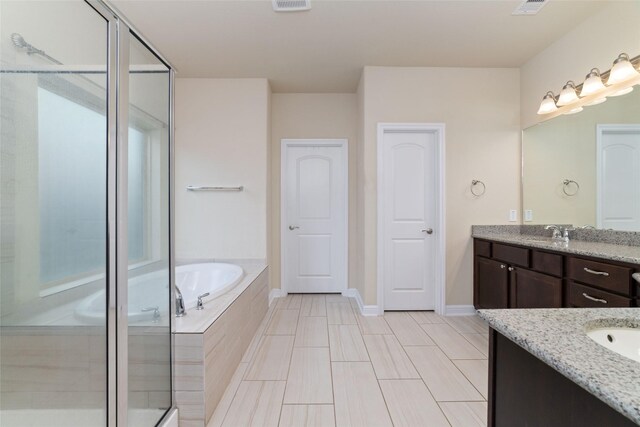 full bathroom with a garden tub, a sink, two vanities, baseboards, and a shower stall