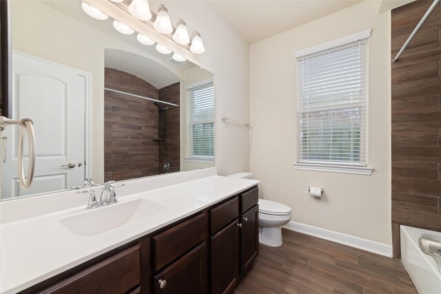 full bath with toilet, baseboards, wood finished floors, and vanity