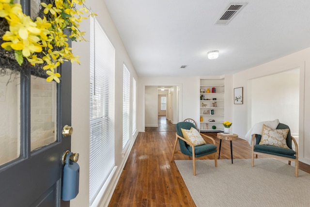 sitting room with dark wood-type flooring and built in features