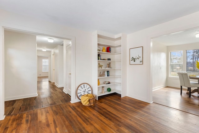 interior space with built in shelves and dark hardwood / wood-style floors