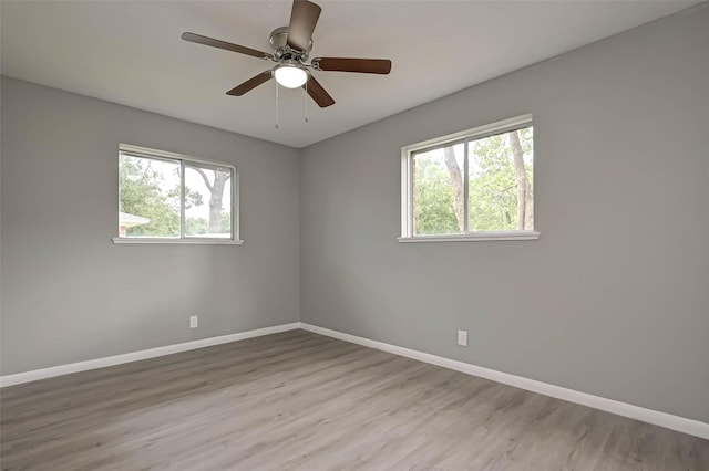 spare room with ceiling fan, a healthy amount of sunlight, and light wood-type flooring