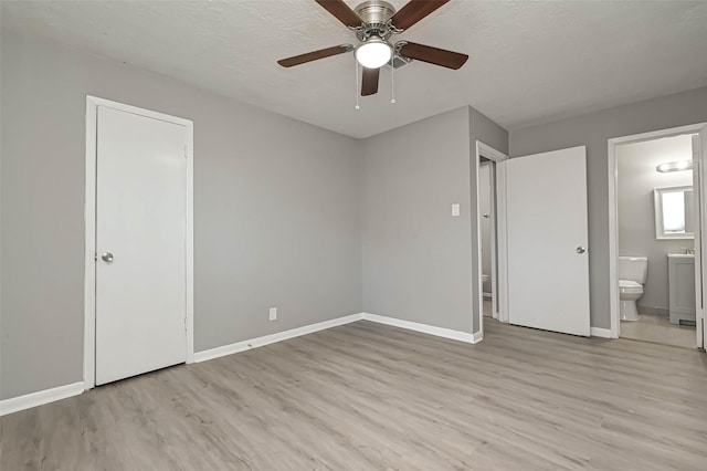 unfurnished bedroom featuring ensuite bathroom, ceiling fan, a textured ceiling, and light hardwood / wood-style flooring