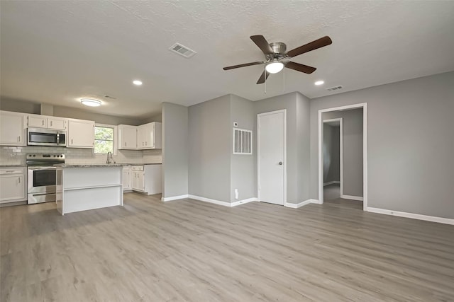 unfurnished living room with sink, a textured ceiling, light hardwood / wood-style floors, and ceiling fan