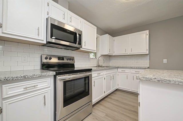 kitchen featuring sink, light hardwood / wood-style flooring, stainless steel appliances, and white cabinets