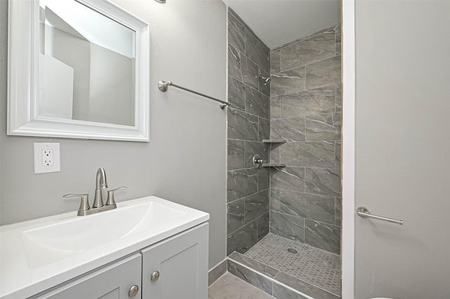 bathroom with tiled shower and vanity