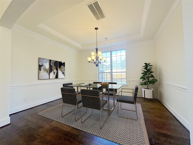 dining room featuring crown molding, a raised ceiling, dark wood-type flooring, and a notable chandelier