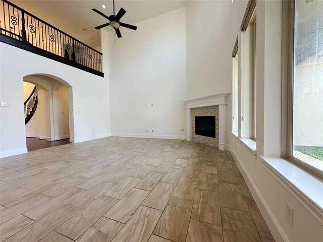 unfurnished living room featuring a towering ceiling, light hardwood / wood-style flooring, and ceiling fan