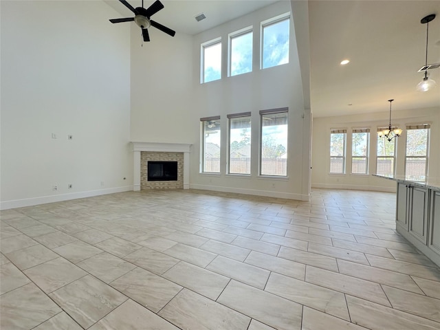 unfurnished living room featuring a high ceiling, ceiling fan with notable chandelier, and light tile patterned floors