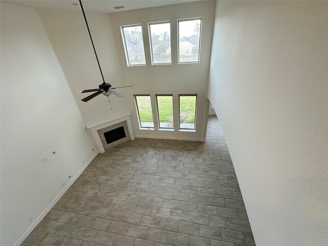 unfurnished living room featuring ceiling fan and a high ceiling