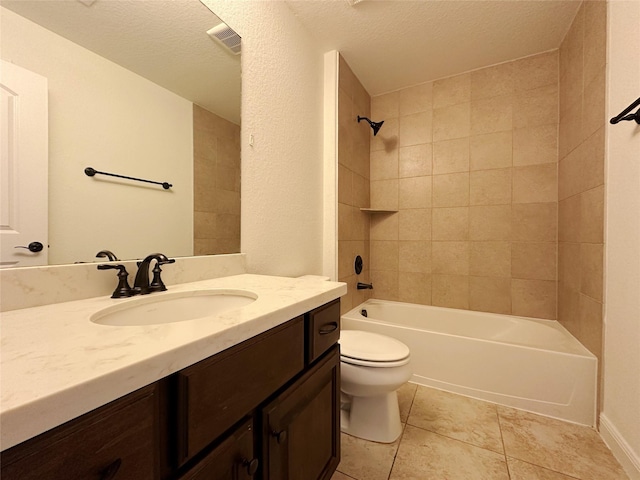 full bathroom featuring tiled shower / bath, tile patterned flooring, vanity, toilet, and a textured ceiling