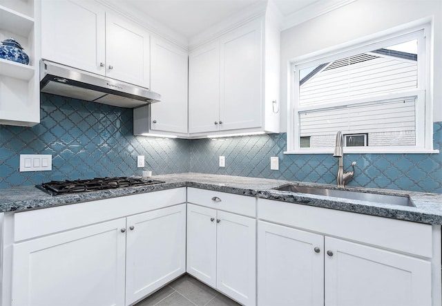 kitchen with black gas stovetop, sink, white cabinets, and decorative backsplash