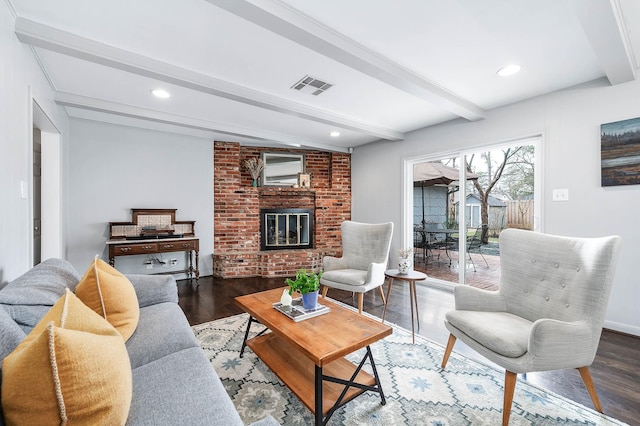 living room featuring hardwood / wood-style floors, beamed ceiling, and a brick fireplace