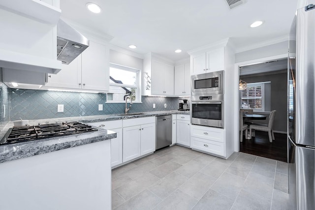 kitchen featuring appliances with stainless steel finishes, sink, white cabinets, light stone counters, and wall chimney exhaust hood