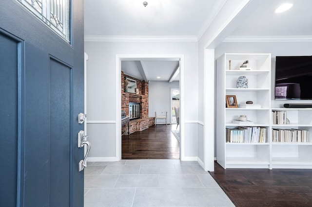 tiled foyer featuring a brick fireplace and crown molding