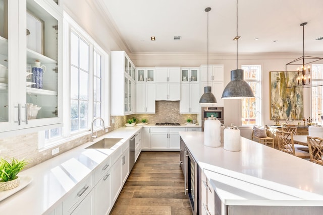 kitchen featuring sink, appliances with stainless steel finishes, white cabinetry, a center island, and ornamental molding