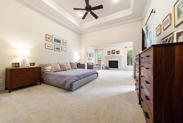 carpeted bedroom with ornamental molding, a raised ceiling, ceiling fan, and a high ceiling