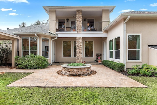 rear view of house with a yard, a patio, and a balcony