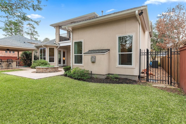 back of property featuring a balcony, central air condition unit, a patio area, and a lawn