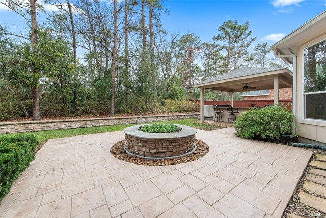 view of patio / terrace featuring an outdoor bar, ceiling fan, and a fire pit