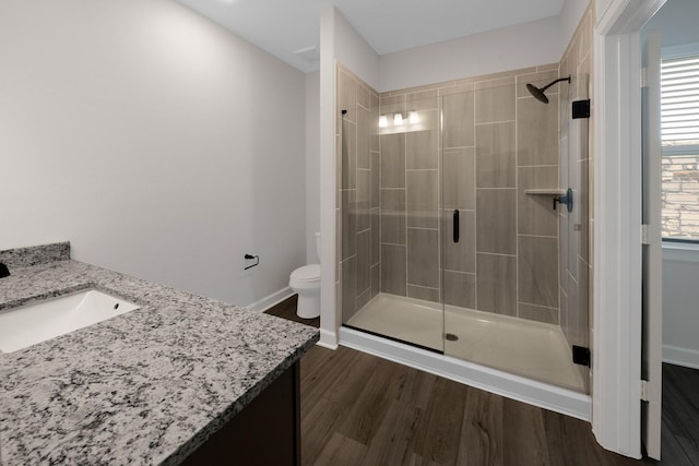 bathroom with vanity, hardwood / wood-style flooring, a shower with shower door, and toilet